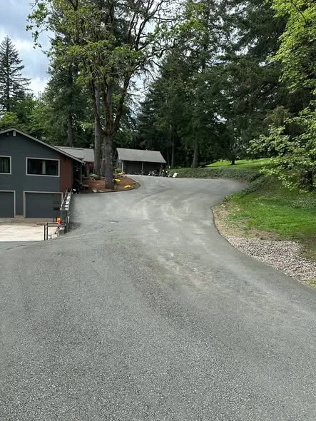 New asphalt driveway leading up past a grey house