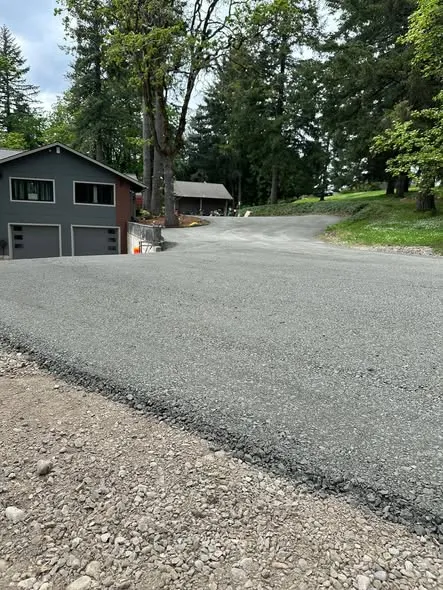 New asphalt driveway sweeping up to a two-storey house
