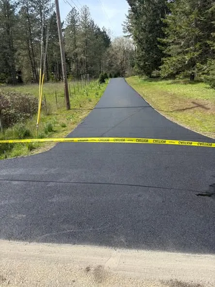 Long fresh asphalt driveway taped off while it cures